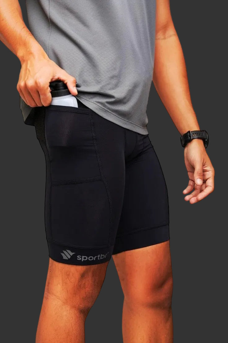 Bermuda de compressão preta SPORTBR com bolsos laterais para corrida, vestida por um atleta guardando uma garrafa.