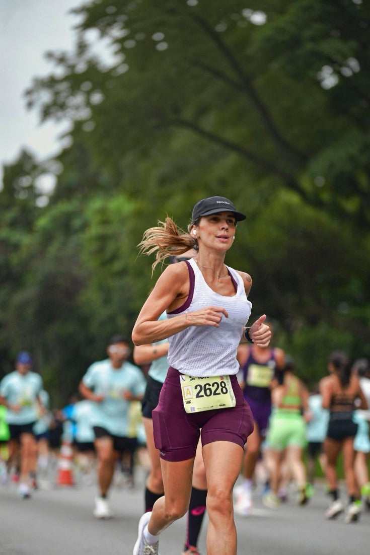Corredora usando bermuda de compressão vinho SPORTBR com bolsos laterais durante prova de corrida de rua ao ar livre