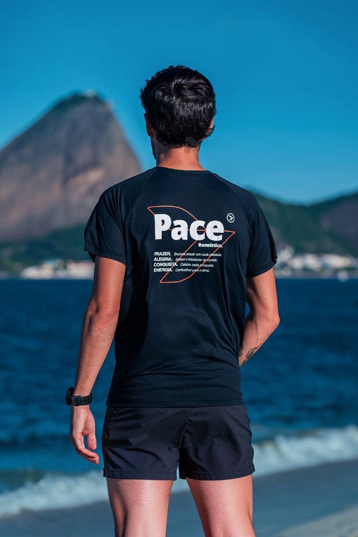 Homem vestindo camiseta preta de poliamida SPORTBR Julia Sette Pace com estampa nas costas em cenário de praia