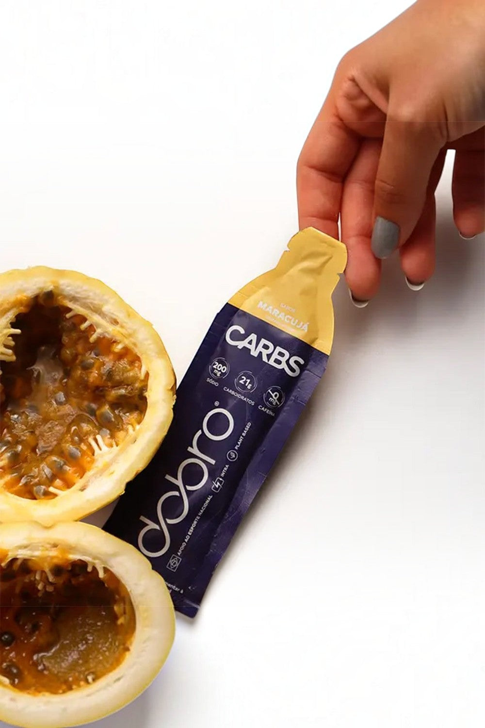 Sachê de gel de carboidrato SPORTBR Dobro sabor maracujá, sem cafeína, ao lado de um maracujá cortado ao meio.