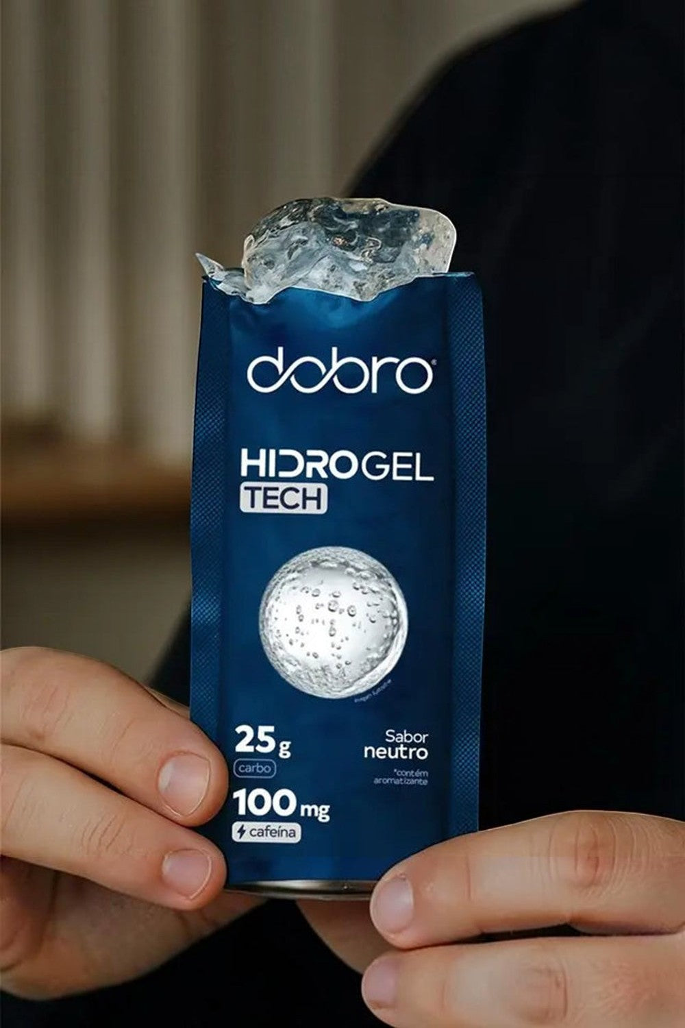 Sachê de gel de carboidrato SPORTBR Dobro Hidro Gel Tech sabor neutro com cafeína sendo aberto por mãos