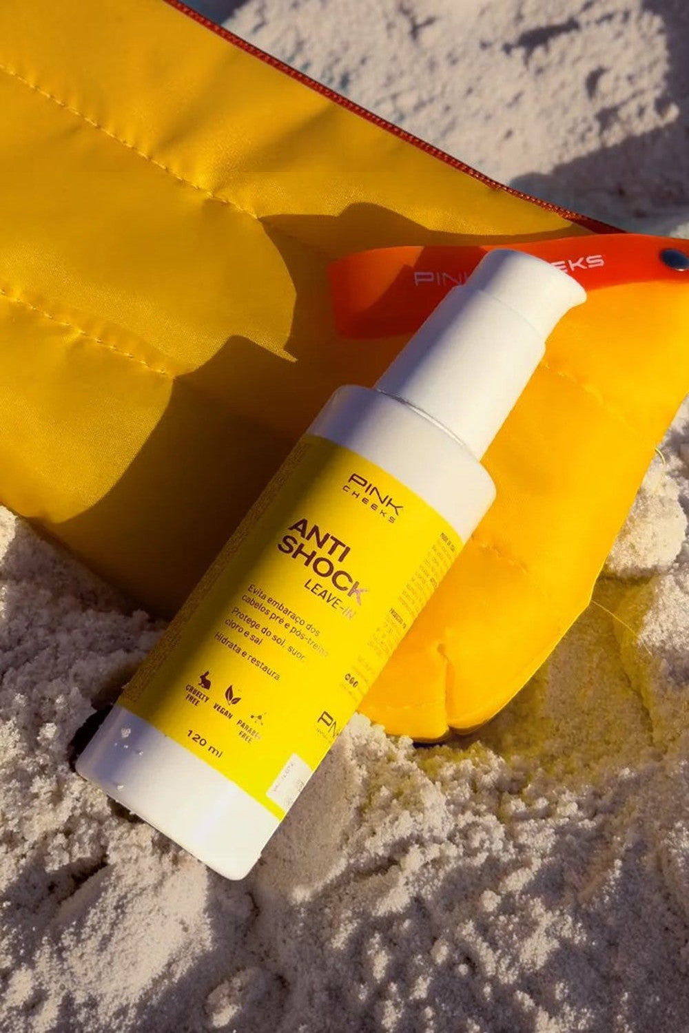 Leave-in capilar SPORTBR Pink Cheeks Anti Shock 120ml com filtro solar sobre areia clara e acessório amarelo