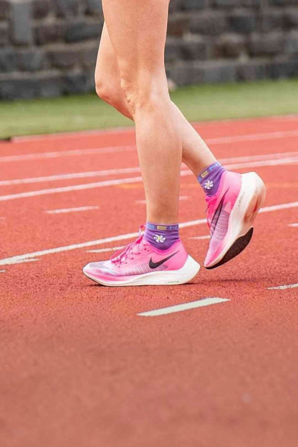 Meia de corrida SPORTBR cano baixo na cor roxa Bubblegum, usada por atleta em pista de atletismo.
