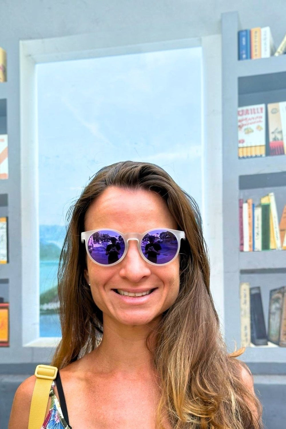Mulher usando óculos de sol Goodr com armação branca e lentes espelhadas roxas, modelo Circle G da SPORTBR.