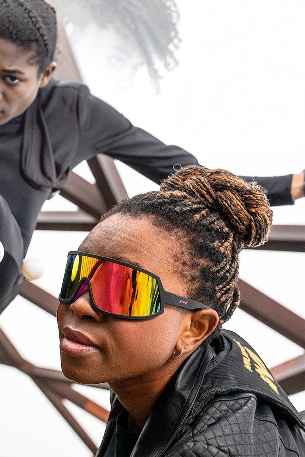 Mulher negra usando óculos de sol esportivos Goodr I Do My Own Stunts com armação preta e lentes espelhadas rosa