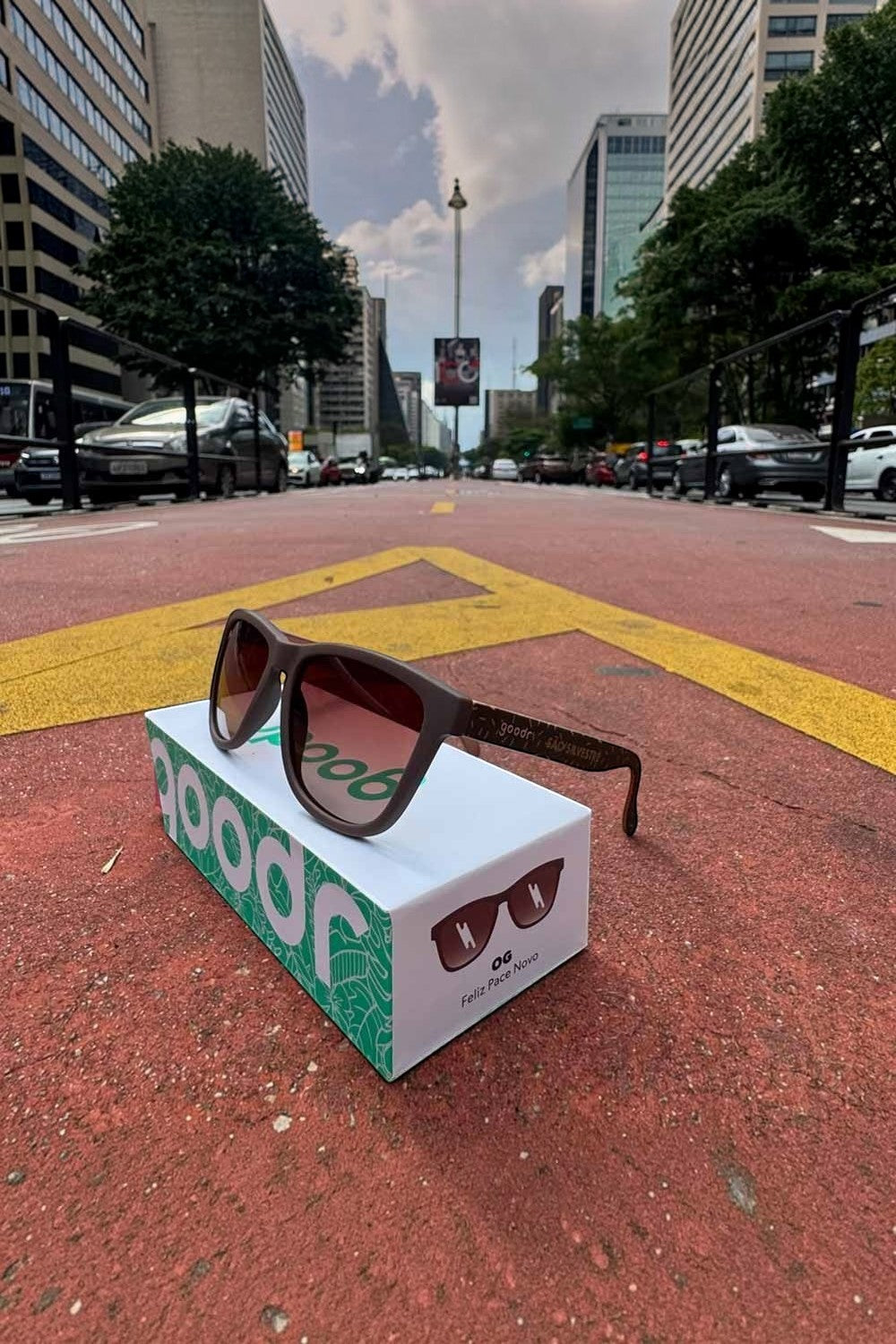 Óculos de sol polarizados SPORTBR goodr Feliz Pace Novo São Silvestre marrom sobre caixa em rua de corrida