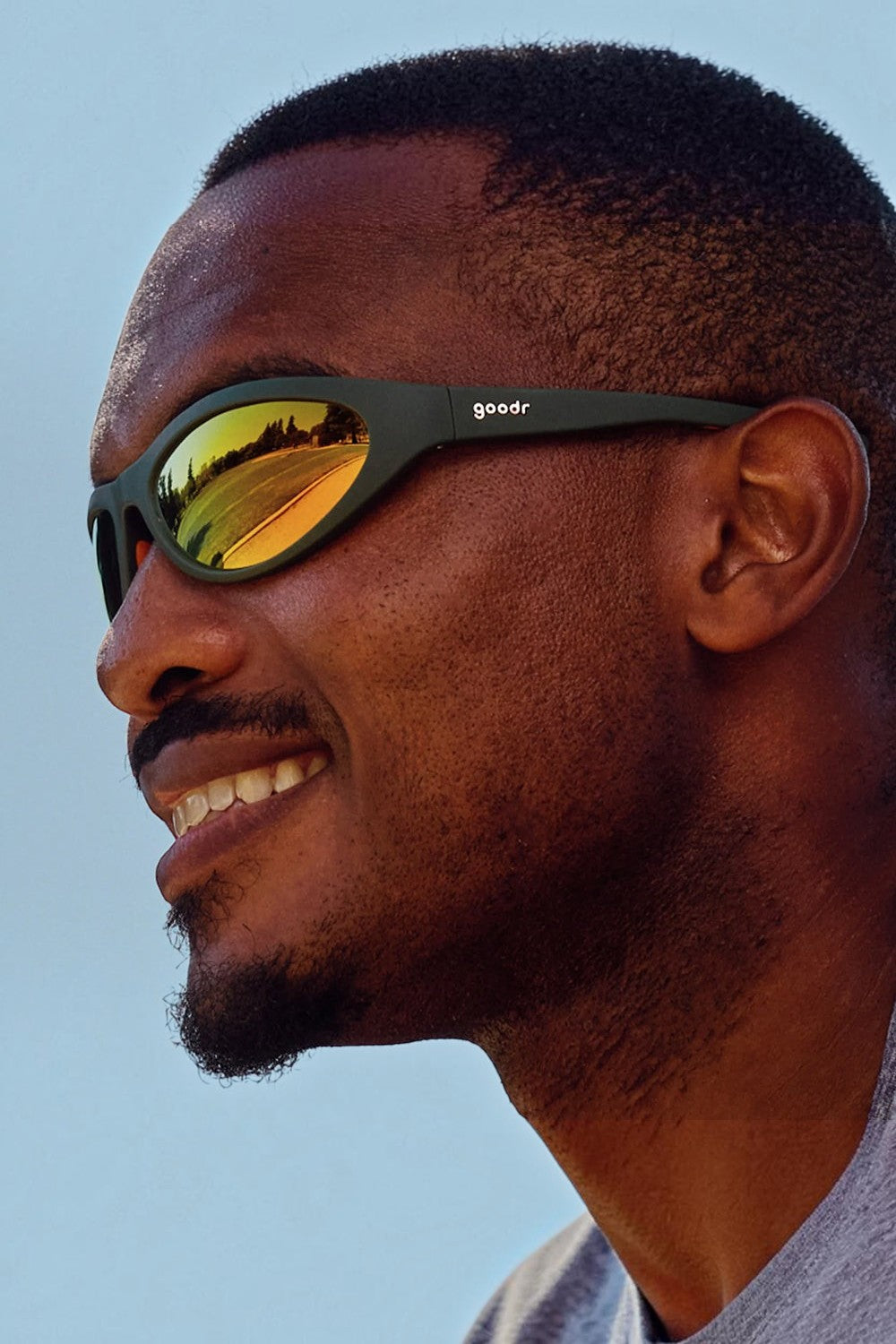 Homem usando óculos de sol SPORTBR Goodr Grass Stain Hall of Fame com armação verde e lentes espelhadas âmbar.