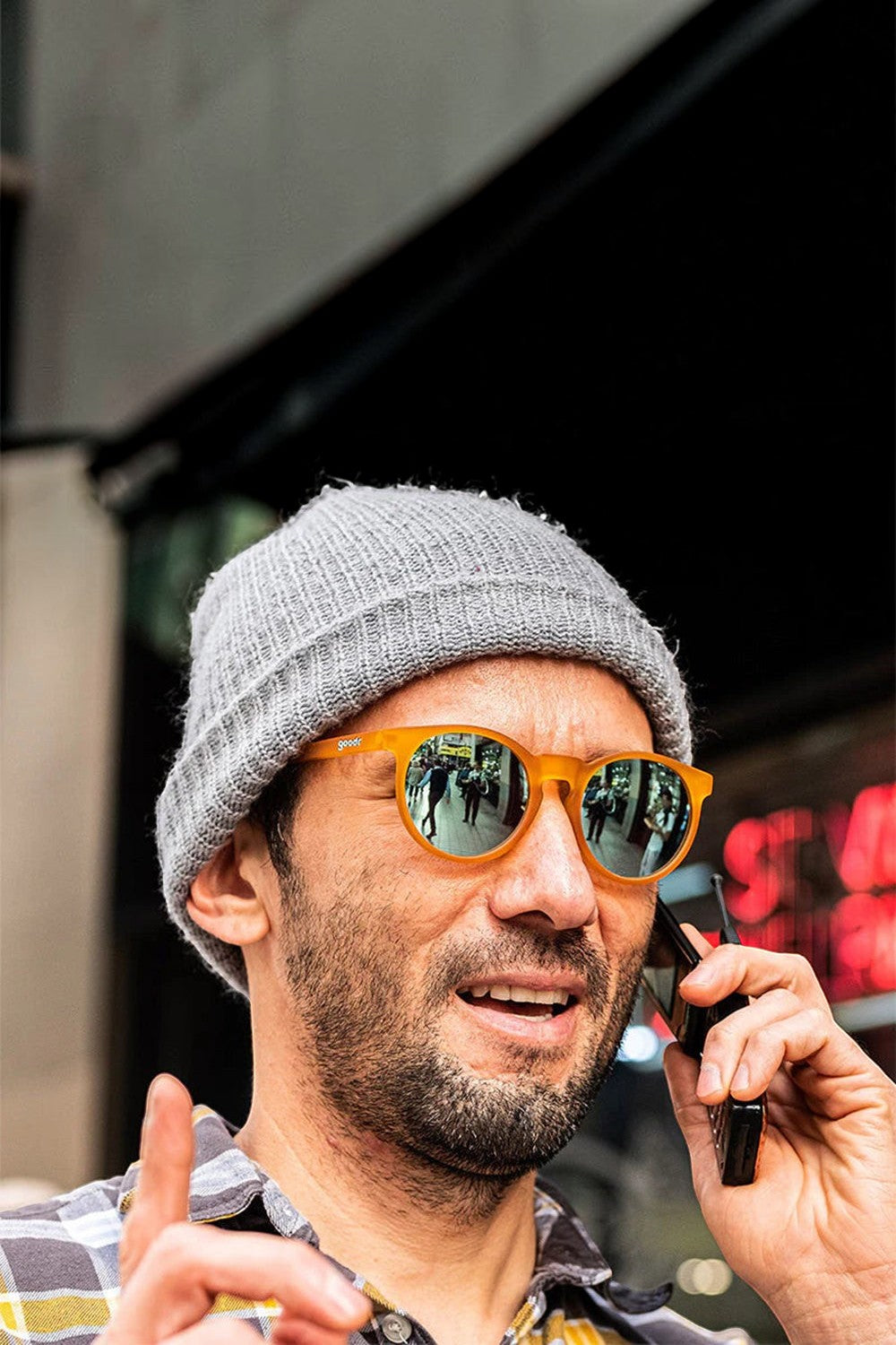 Homem usando óculos de sol SPORTBR Goodr laranja com lentes espelhadas azuis em formato circular, estilo casual.