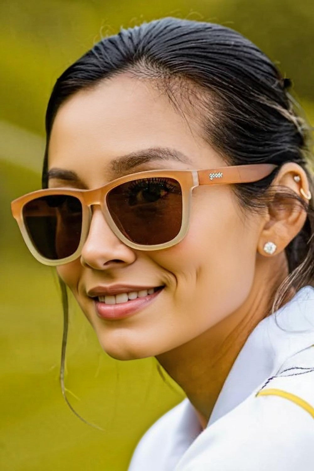 Mulher usando óculos de sol Goodr Three Parts Tee com armação marrom degradê e lentes polarizadas em ambiente externo.