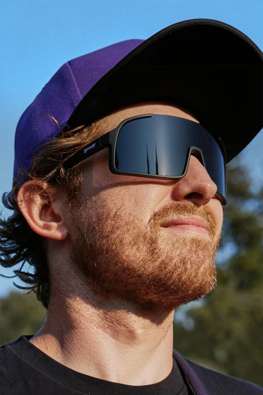 Homem usando óculos de sol esportivos pretos Goodr com lentes polarizadas durante corrida, vendido pela SPORTBR.