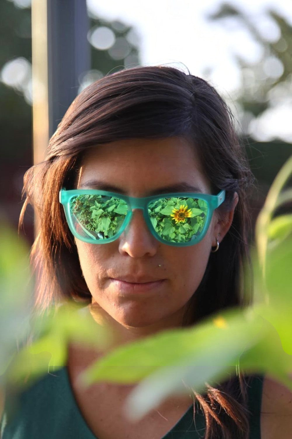 Mulher usando óculos de sol SPORTBR Goodr verdes com lentes espelhadas polarizadas em ambiente externo.