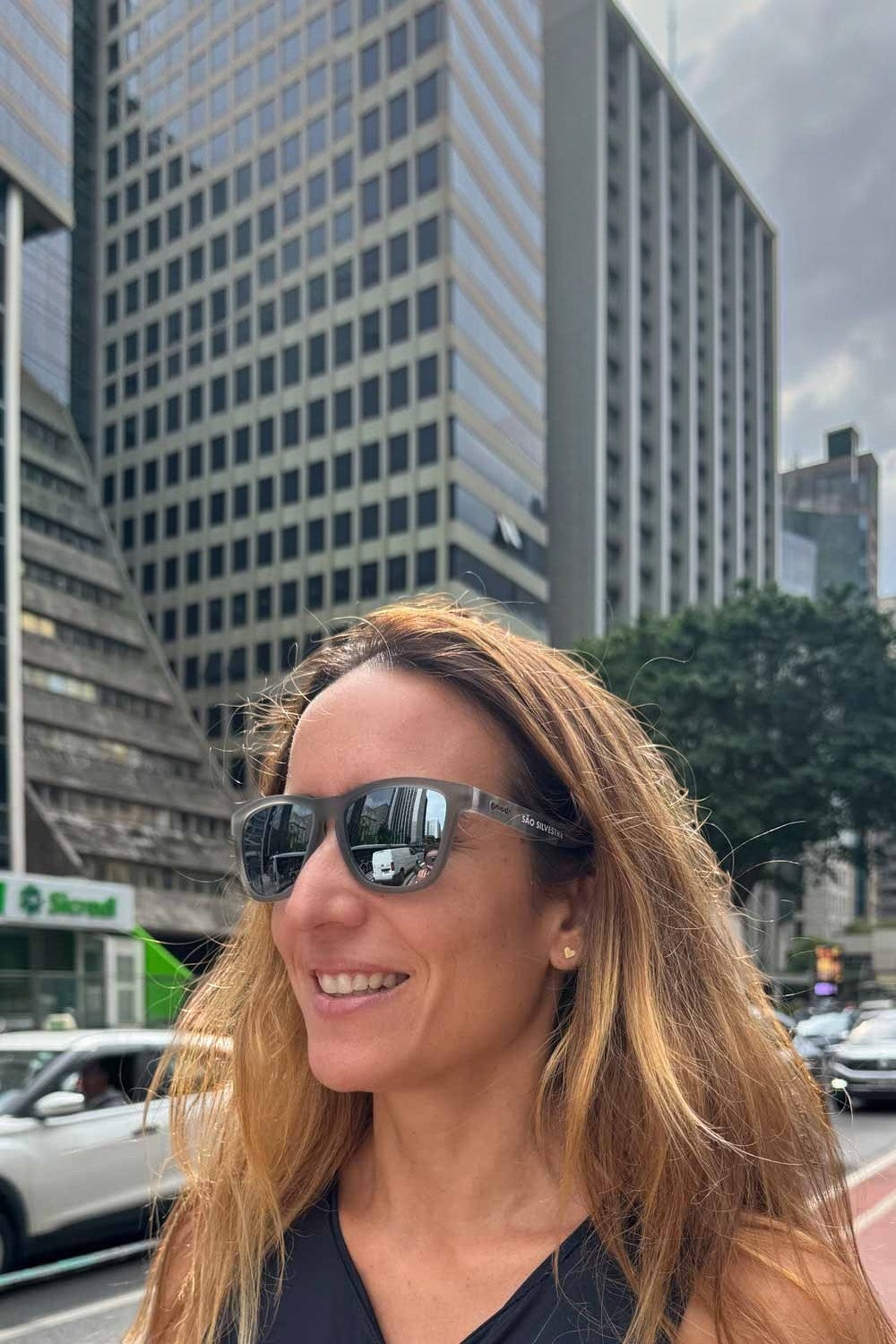 Mulher usando óculos de sol SPORTBR Goodr Festa 100 Fim São Silvestre com lentes espelhadas na Avenida Paulista.