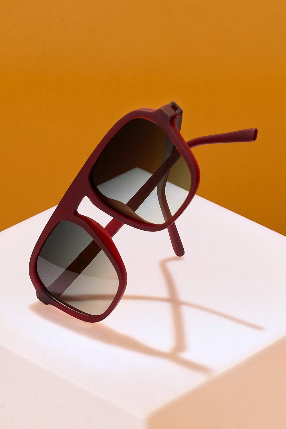 Óculos de sol SPORTBR Goodr Conversation Pit com armação vinho e lentes verdes polarizadas em suporte branco
