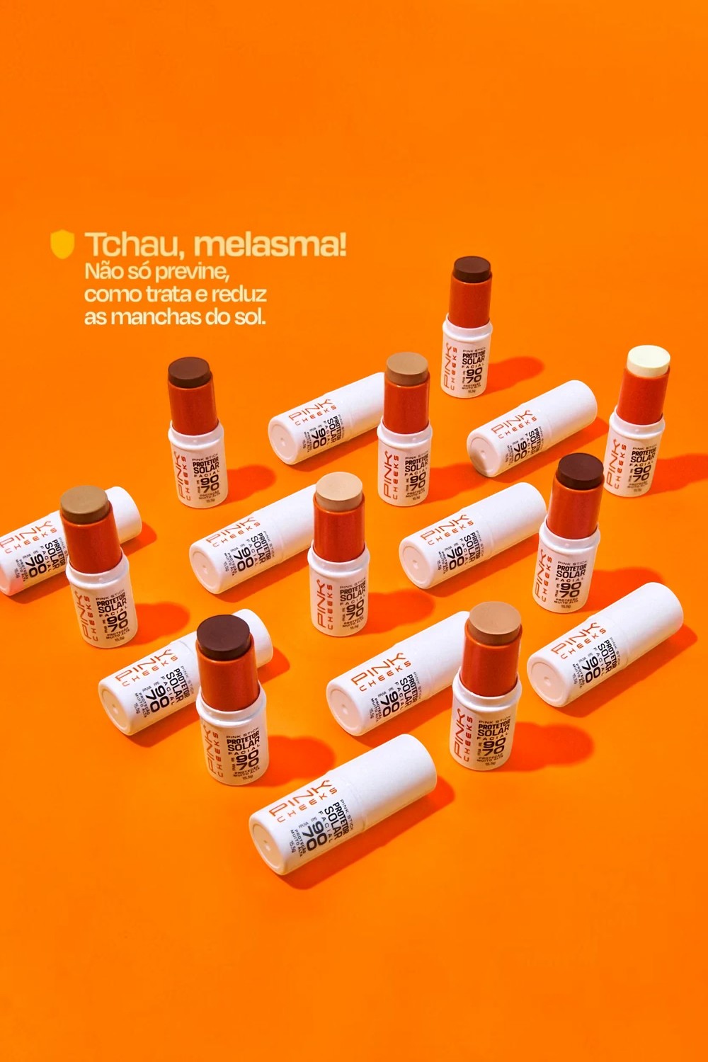 Protetor solar facial em bastão SPORTBR Pink Cheeks com FPS90 em diversas tonalidades sobre fundo laranja vibrante.