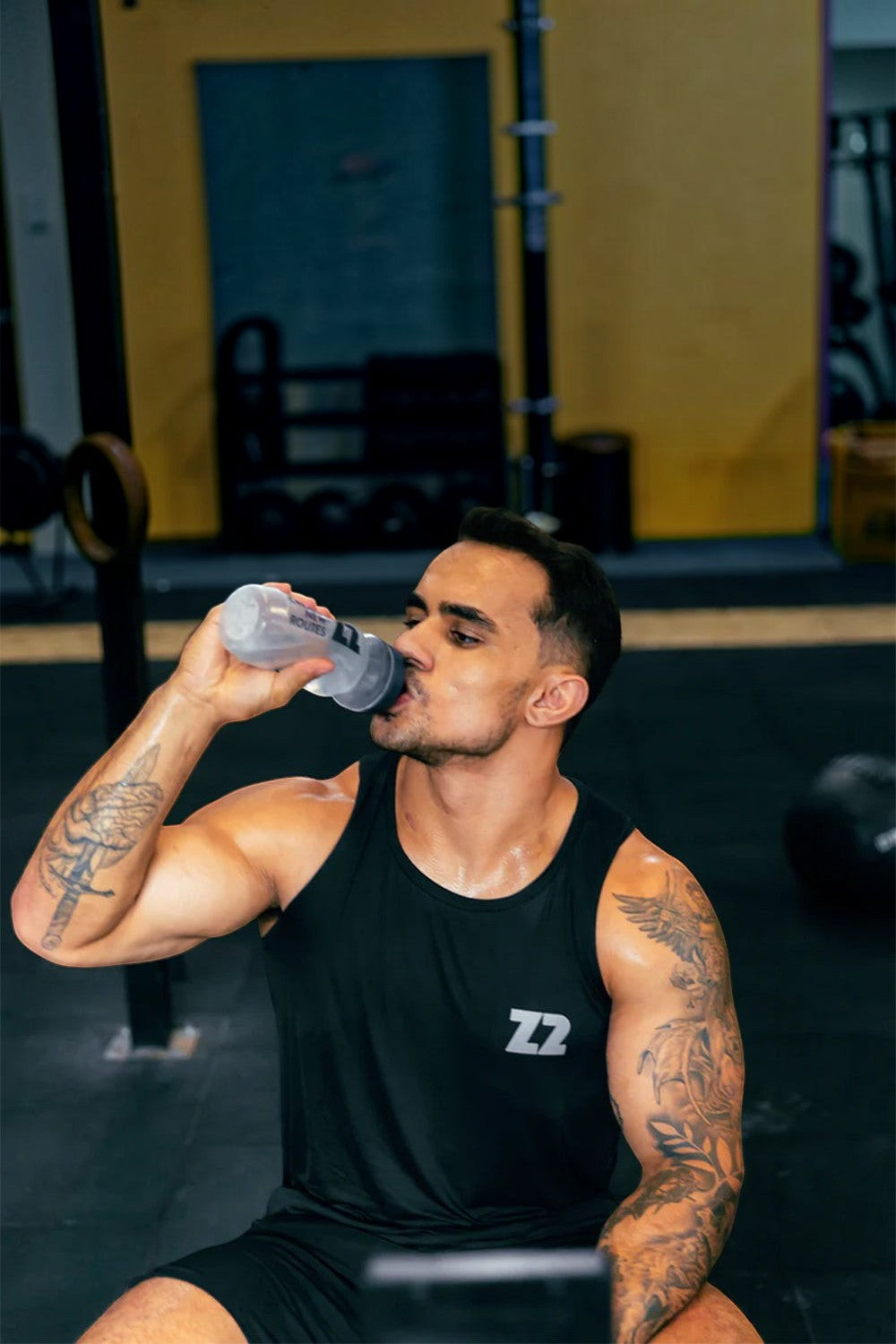 Atleta SPORTBR bebendo repositor eletrolítico Saltz 1000 Z2 sabor frutas amarelas em academia após treino intenso