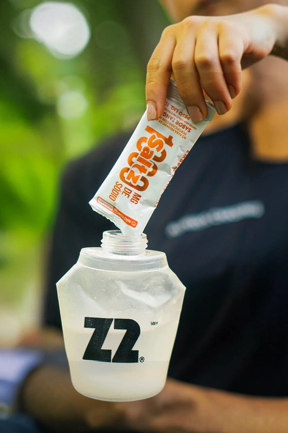 SPORTBR Sachê Saltz 1000 Z2 sabor tangerina sendo despejado em uma garrafa de hidratação Z2 para preparo de bebida