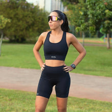 Mulher usando bermuda de compressão preta da SPORTBR com 6 bolsos e top esportivo, ideal para corrida.