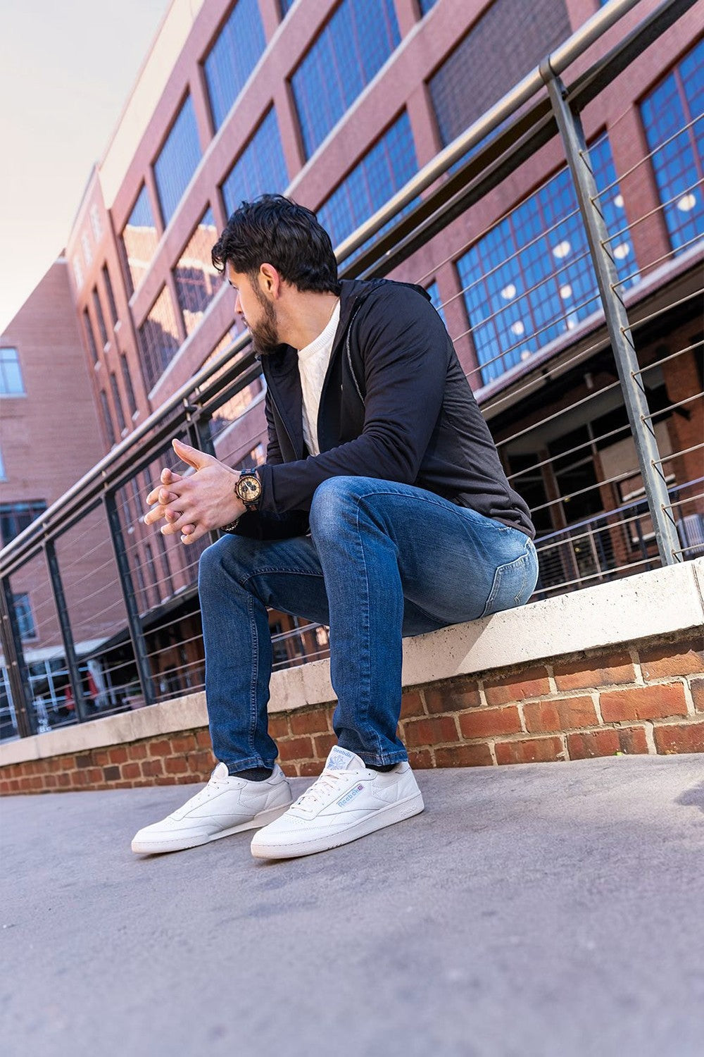 Homem sentado usando tênis com cadarço elástico SPORTBR Lock Laces na cor creme em ambiente urbano