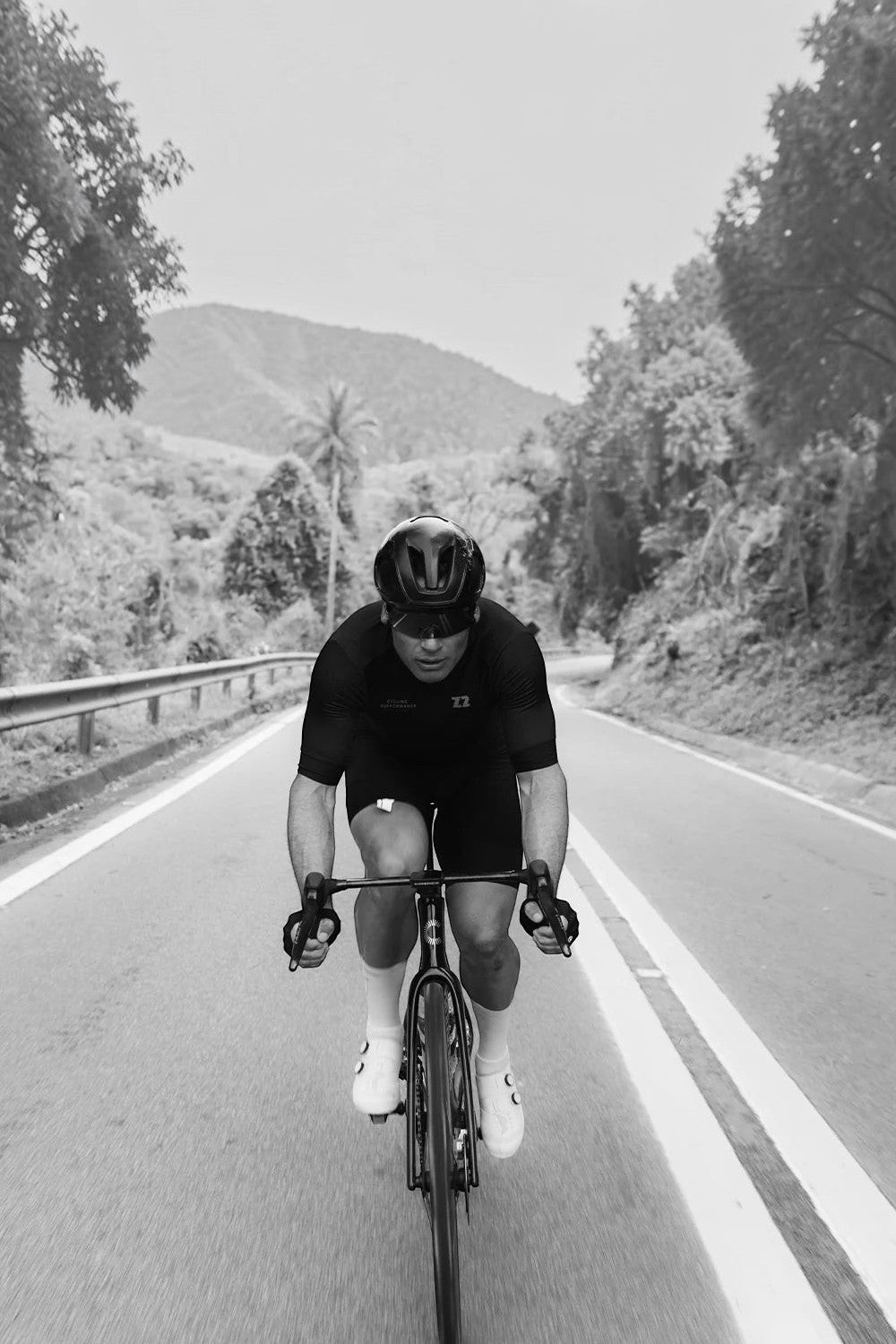 Ciclista SPORTBR pedalando em estrada rural, focado em performance com vestuário esportivo e capacete