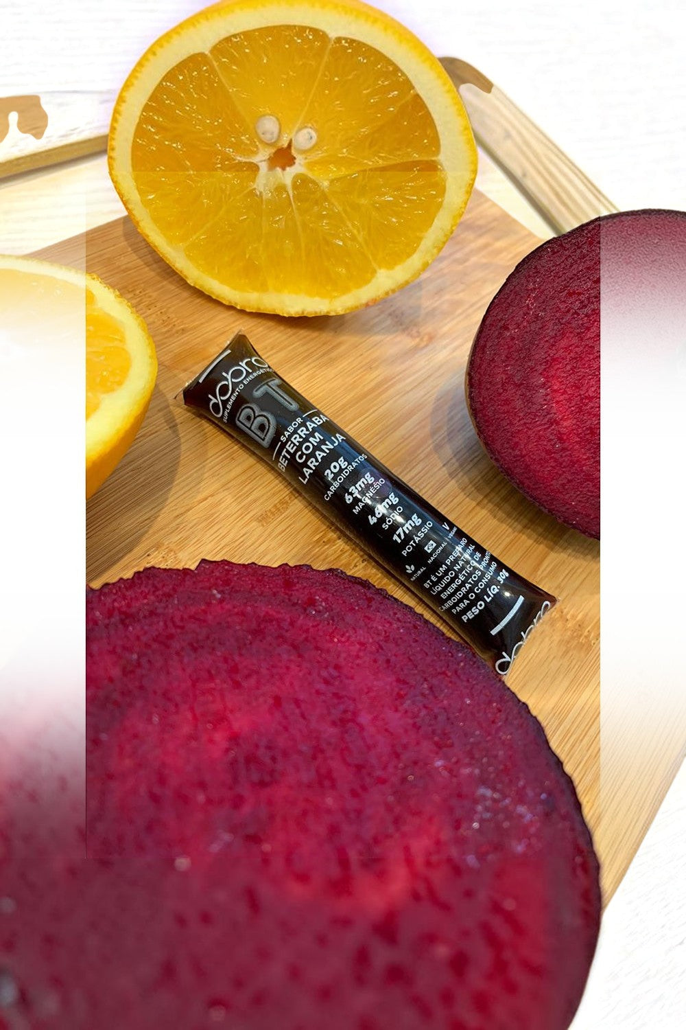 Sachê de gel de carboidrato SPORTBR Dobro sabor beterraba com laranja sobre tábua com fatias de beterraba e laranja
