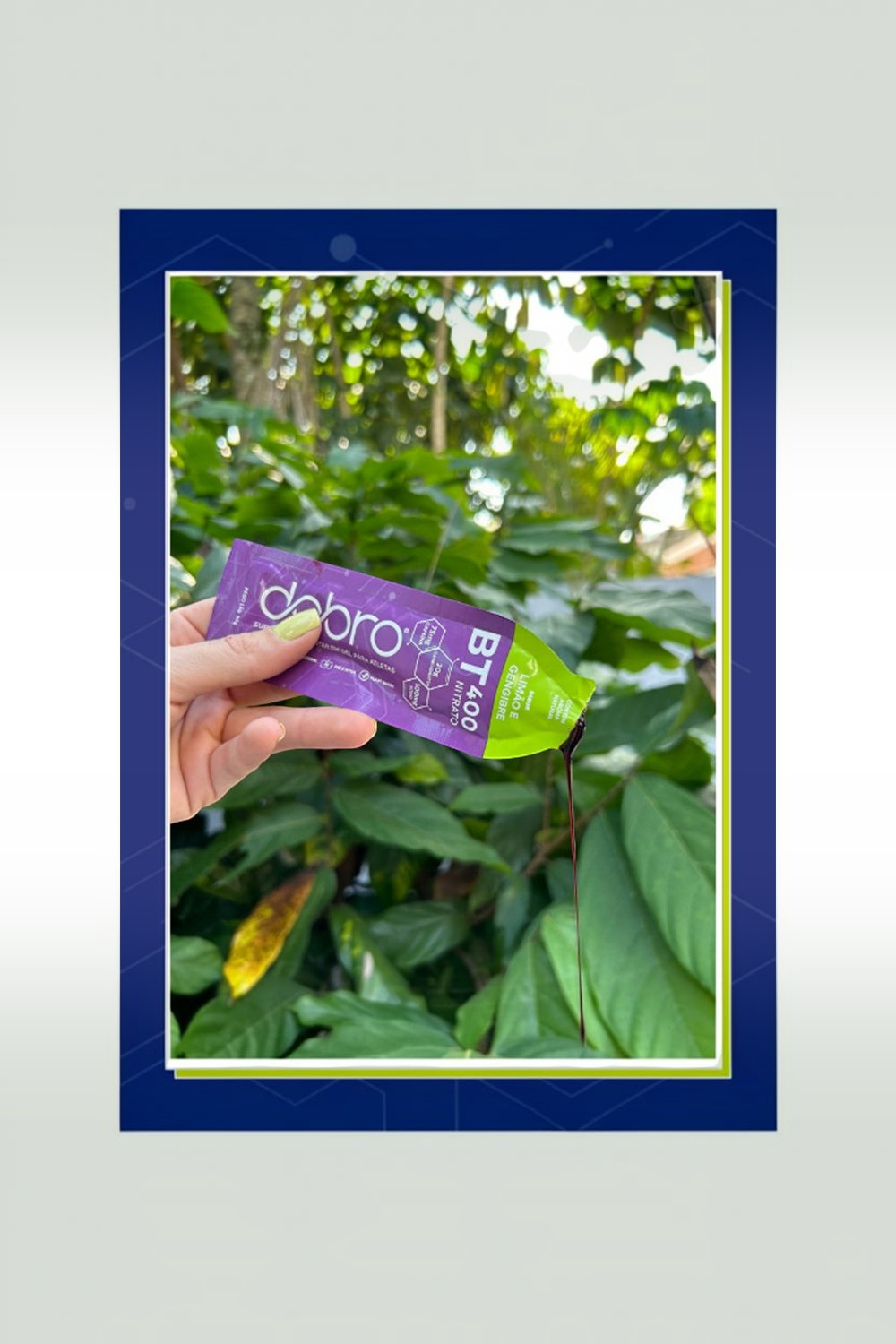 Sachê de gel de carboidrato SPORTBR DOBRO sabor limão e gengibre sendo aberto ao ar livre com fundo de folhagem verde