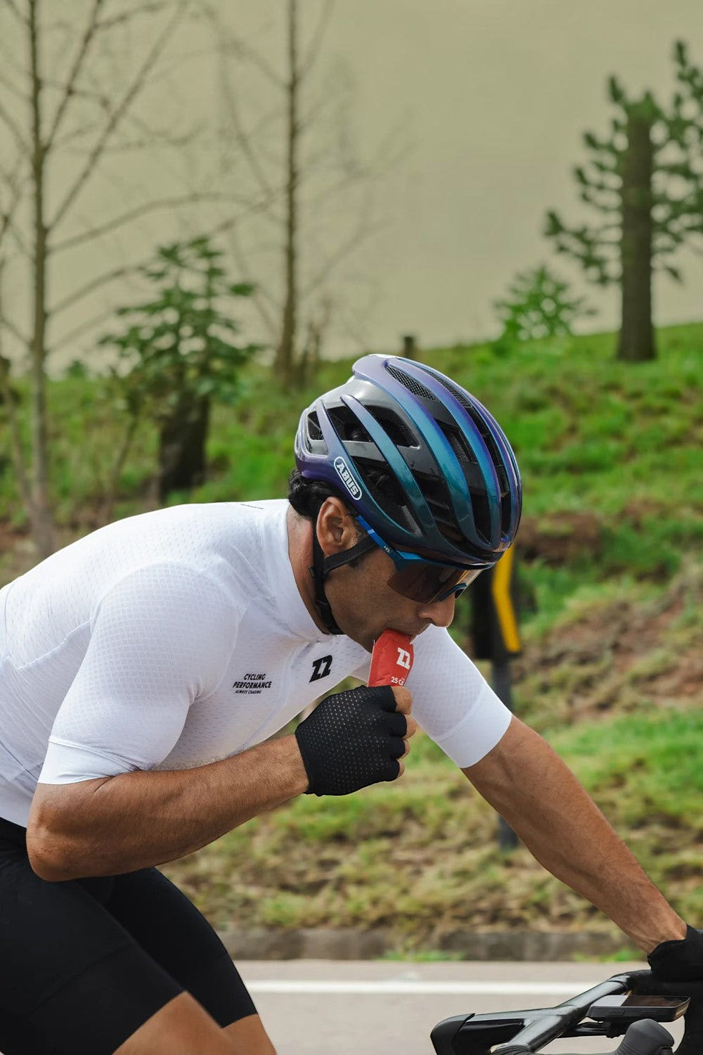Ciclista SPORTBR consumindo sachê de gel de carboidrato Z2 sabor pitaya durante treino de ciclismo ao ar livre