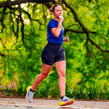 Mulher correndo ao ar livre e consumindo um sachê de gel energético neutro da SPORTBR