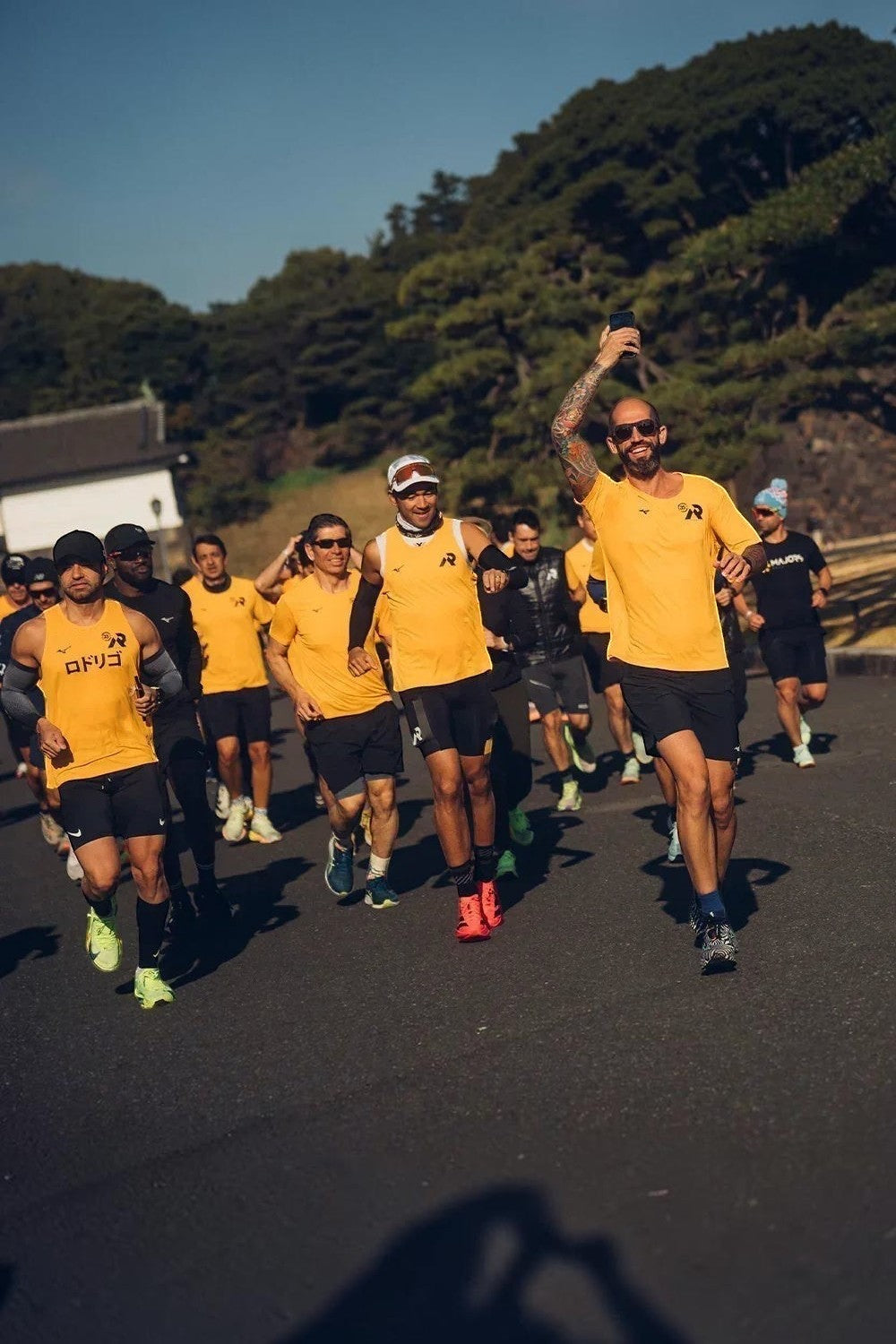 Grupo de corredores SPORTBR usando camisetas amarelas de performance durante uma corrida ao ar livre em dia ensolarado