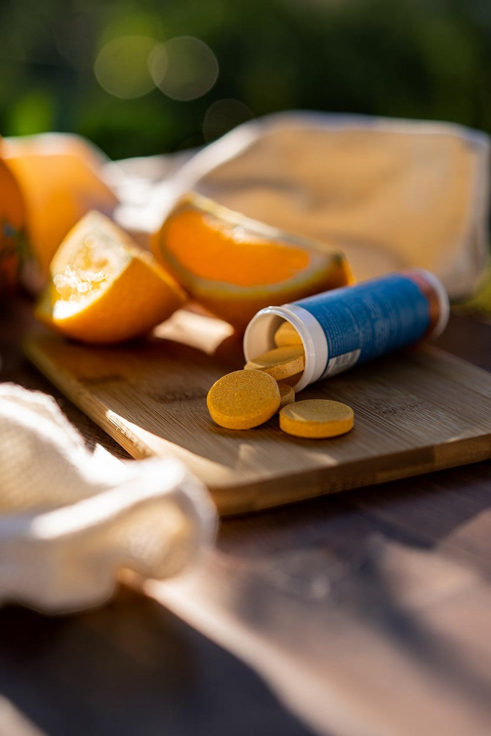 Repositor eletrolítico efervescente SPORTBR Hidra Iso sabor laranja em tabletes sobre tábua de madeira com frutas