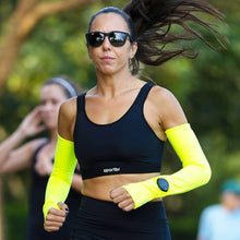 SPORTBR manguito esportivo amarelo neon com abertura para relógio e encaixe para dedo, usado por mulher correndo.