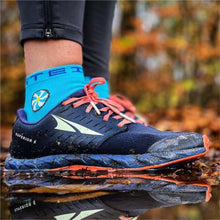 Meia Steigen cano baixo azul com logo branco e detalhe de flor, usada com tênis de corrida azul e laranja.