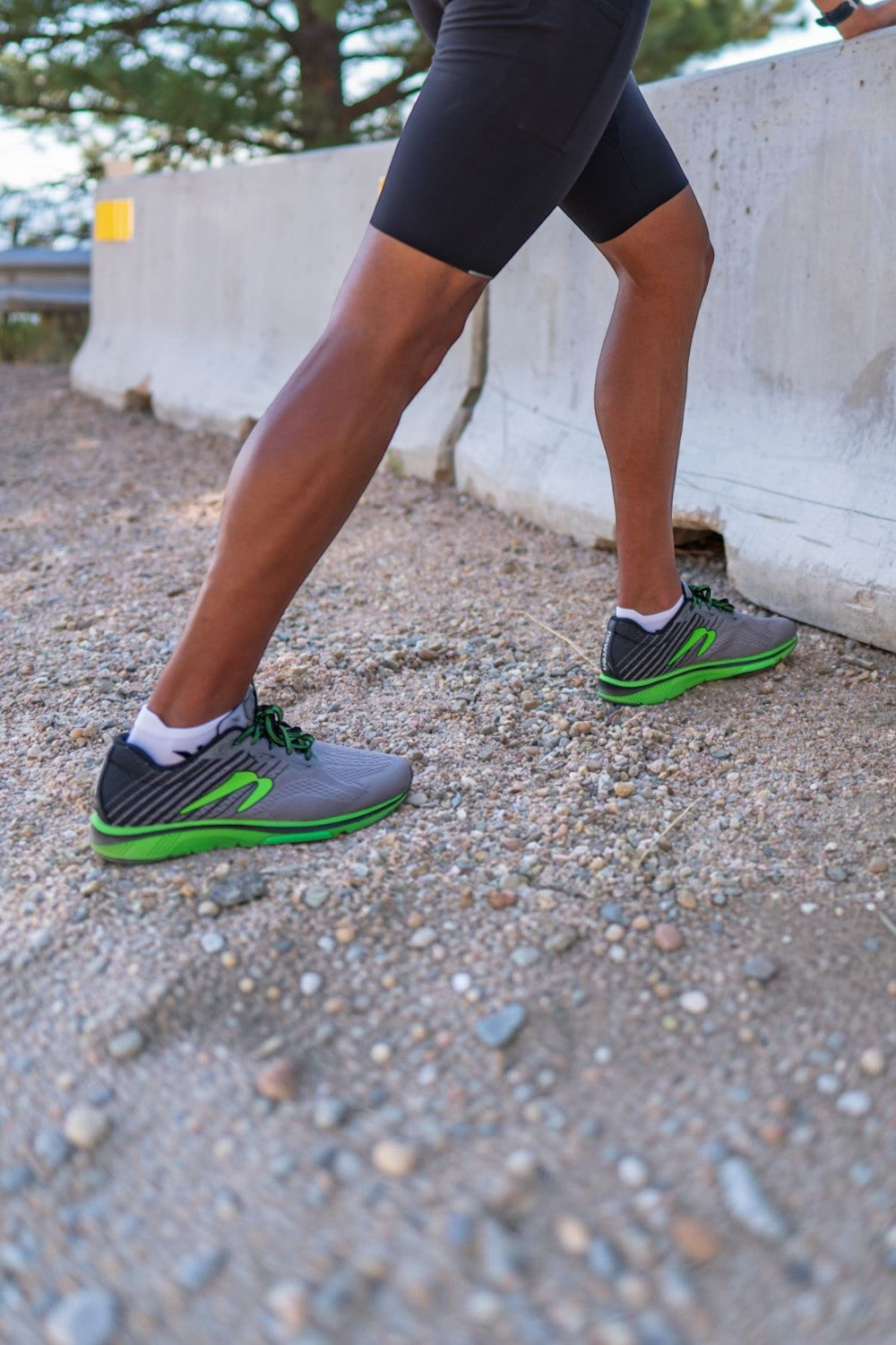 Corredor usando meias brancas Swiftwick Aspire Zero de compressão com tênis esportivos em terreno de cascalho