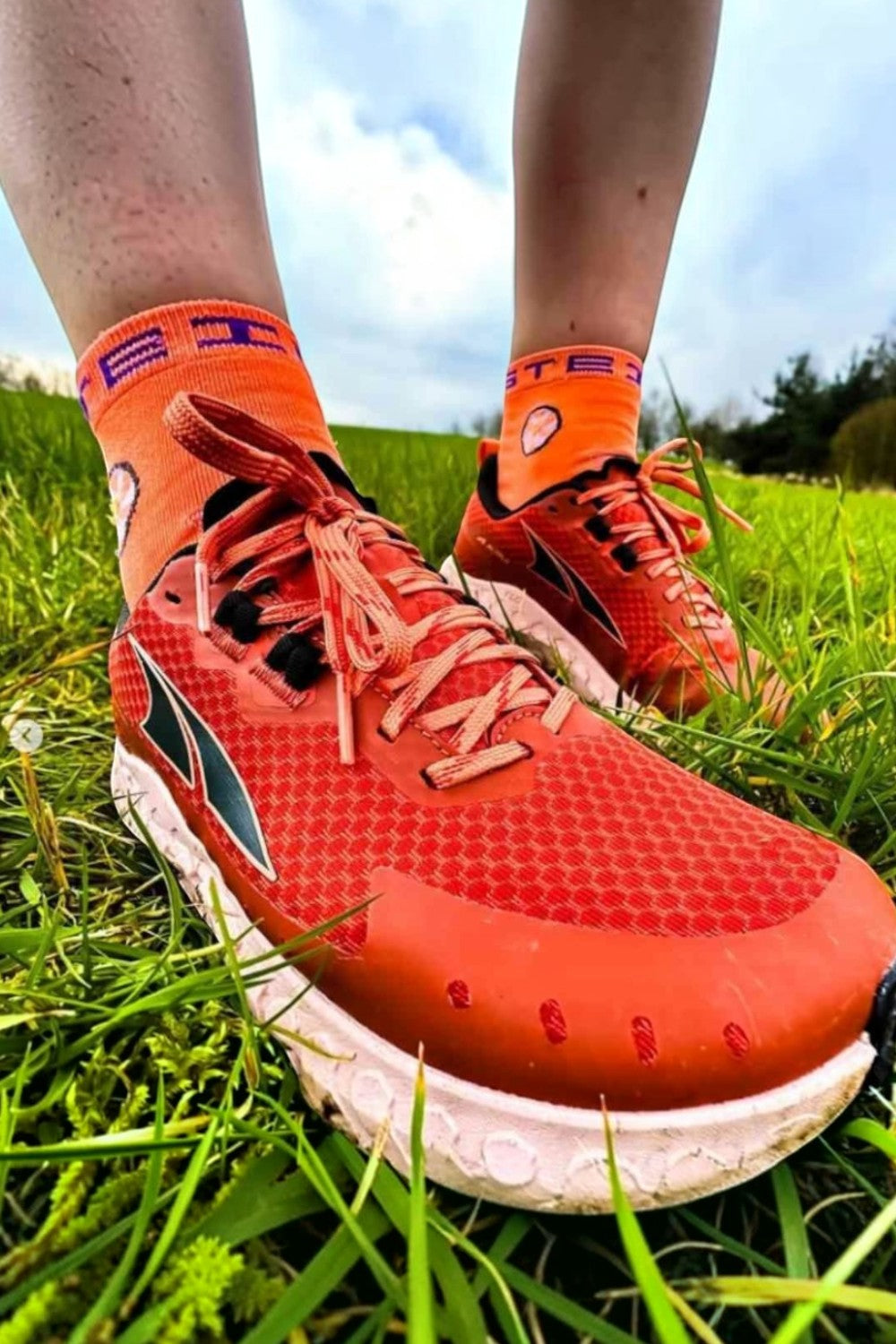 Meia de corrida SPORTBR Steigen cano baixo na cor laranja Goldfish, usada com tênis esportivo em gramado verde.