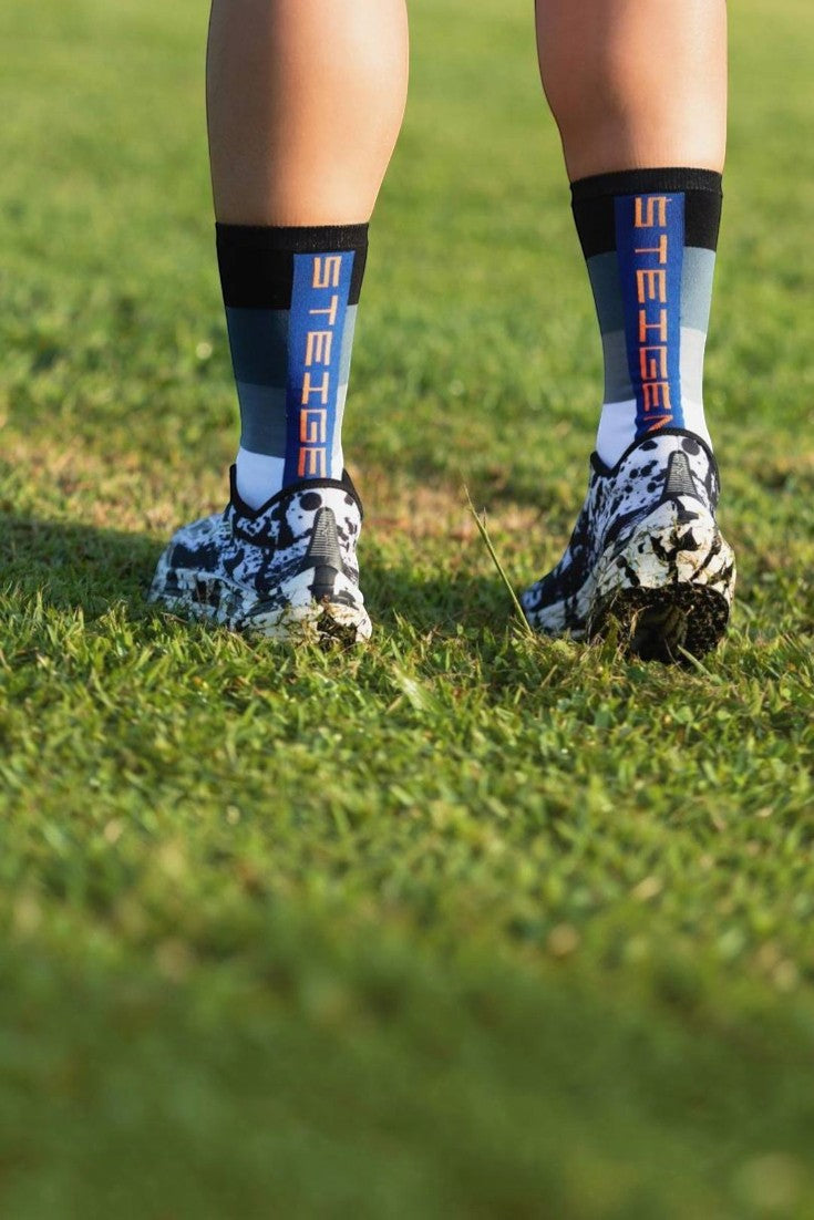 Meia de corrida SPORTBR Steigen cano alto modelo Belle com listras coloridas e logo vertical, usada com tênis em gramado.