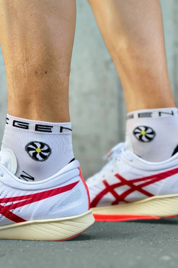 Meia de corrida SPORTBR Steigen cano baixo branca com logo, vestida em pé com tênis esportivo.