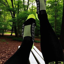 Meia Steigen cano inteiro preta com detalhes em verde neon, feita de nylon e lycra, ideal para corrida.