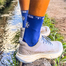 Meia Steigen cano médio azul royal com logo branco e detalhes em branco no cano. Calçada com tênis de corrida cinza.