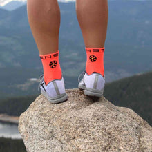 Meia Steigen cano médio Fluro Red com logo preto e branco, feita de nylon e Lycra, ideal para corrida.