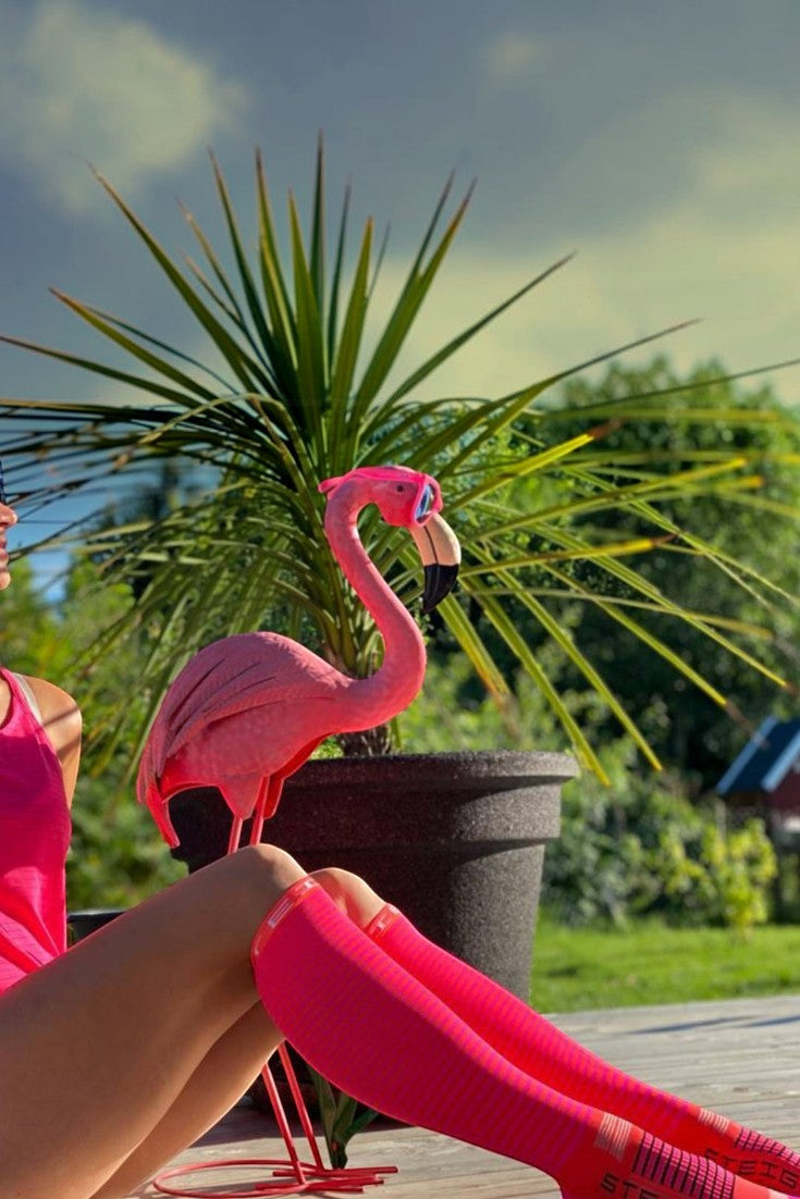 Meia esportiva SPORTBR Steigen cano inteiro rosa em uso por corredora ao ar livre com estatueta de flamingo