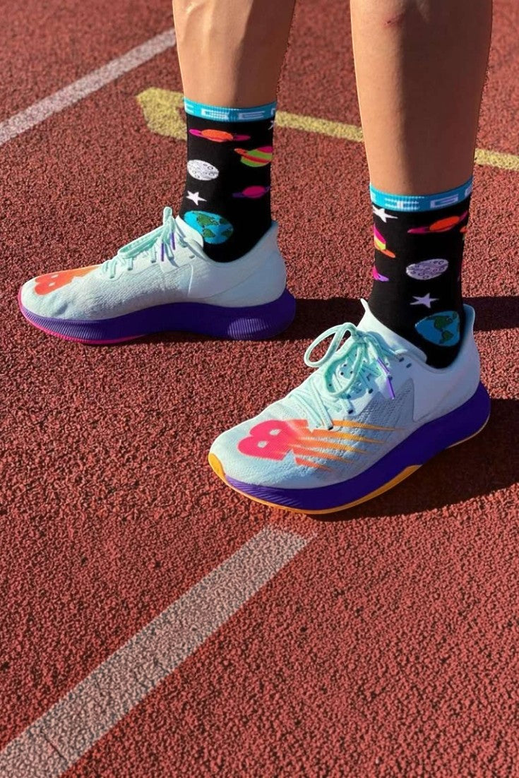 Meia de corrida SPORTBR Steigen cano alto preta com estampa colorida de sistema solar em pista de atletismo