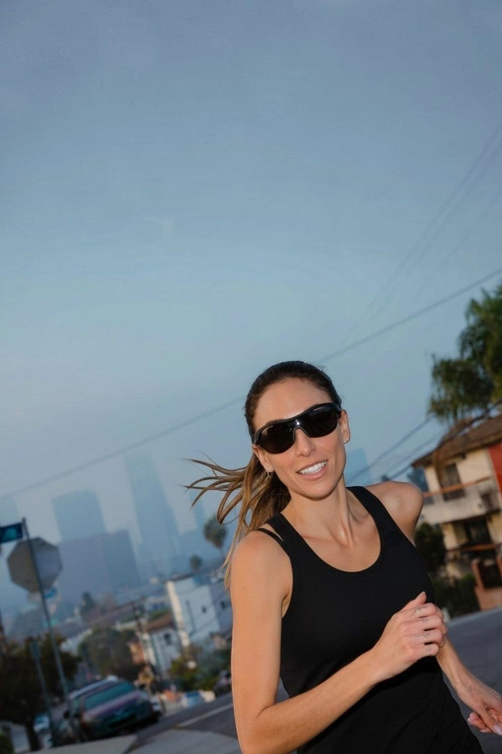 Mulher correndo ao ar livre usando óculos de sol esportivos pretos SPORTBR Goodr When The World Blurs