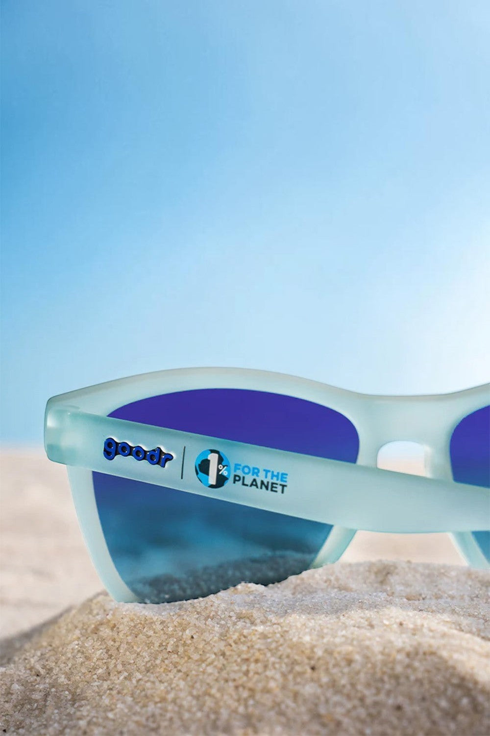 Óculos de sol SPORTBR Goodr These Shades Are Still Trash com armação azul claro e lentes polarizadas na areia.