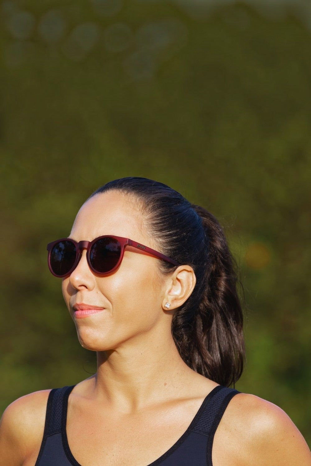 Mulher usando óculos de sol Goodr bordô modelo Circle G com lentes marrons polarizadas em dia de treino SPORTBR