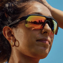 Óculos de sol Goodr pretos com lentes espelhadas laranja e reflexo de cidade. Ideal para corrida.