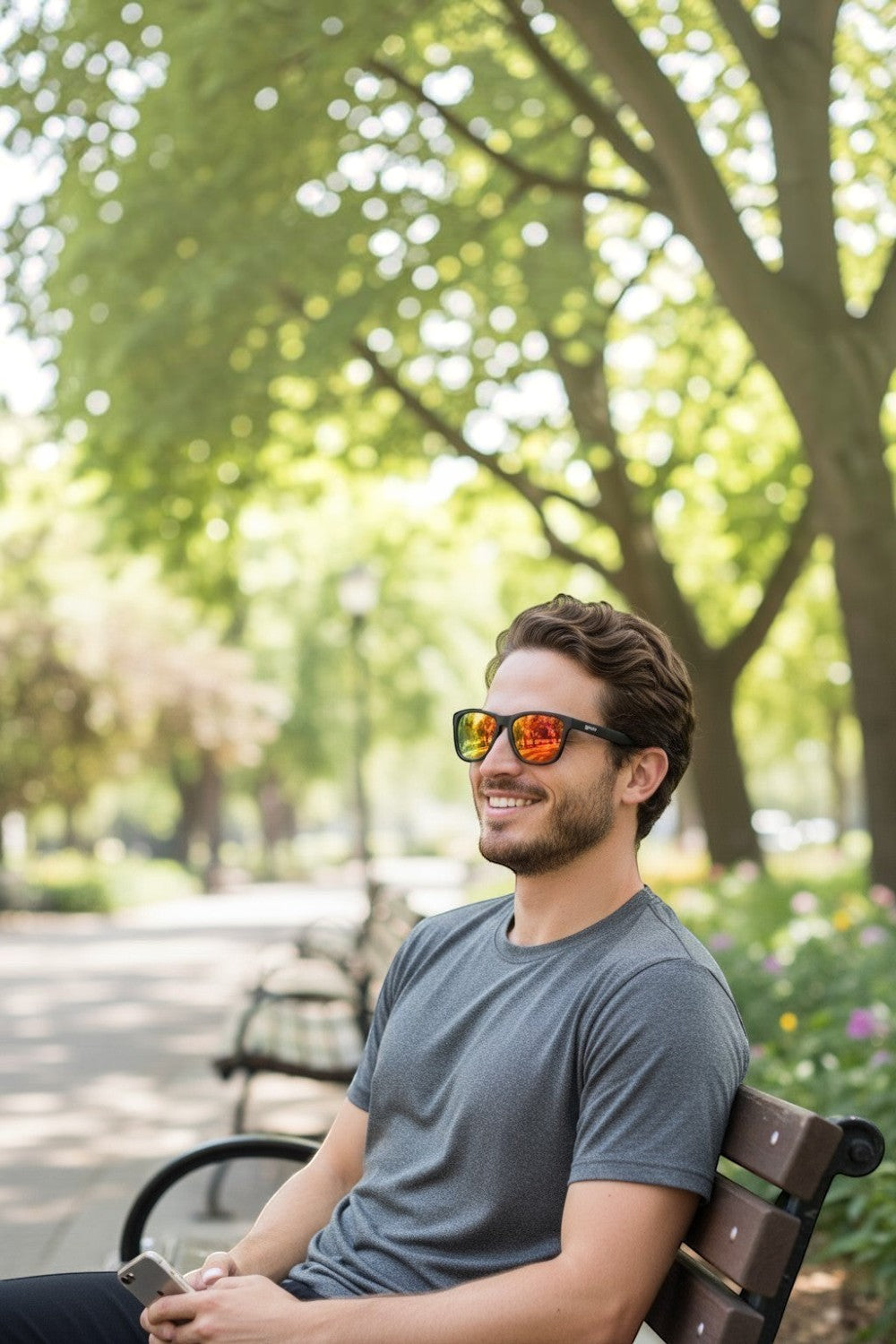 Homem sorridente usando óculos de sol SPORTBR Goodr Whiskey Shots with Satan com lentes espelhadas amarelas em parque