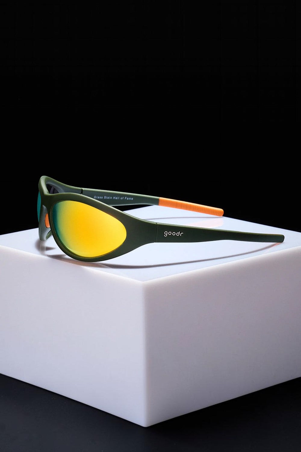 Óculos de sol esportivos SPORTBR Goodr Grass Stain Hall of Fame com armação verde e lentes espelhadas âmbar.