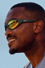 Homem usando óculos de sol SPORTBR Goodr Grass Stain Hall of Fame com armação verde e lentes espelhadas âmbar.