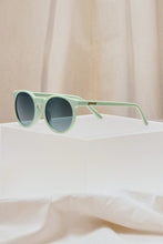 Óculos de sol SPORTBR Goodr Incognito Plant Parent verde com lentes polarizadas em formato Circle G sobre base acrílica.