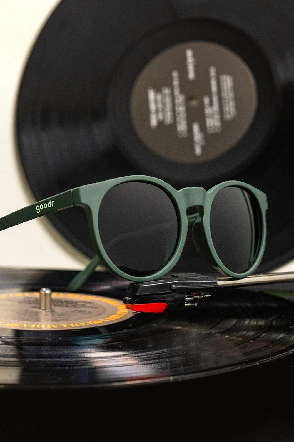 Óculos de sol SPORTBR Goodr Circle G verde com lentes polarizadas sobre um disco de vinil