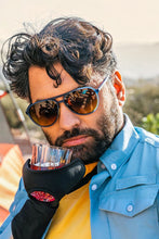Homem usando óculos de sol SPORTBR Goodr Frequent SkyMall Shoppers com armação azul e lentes marrons polarizadas